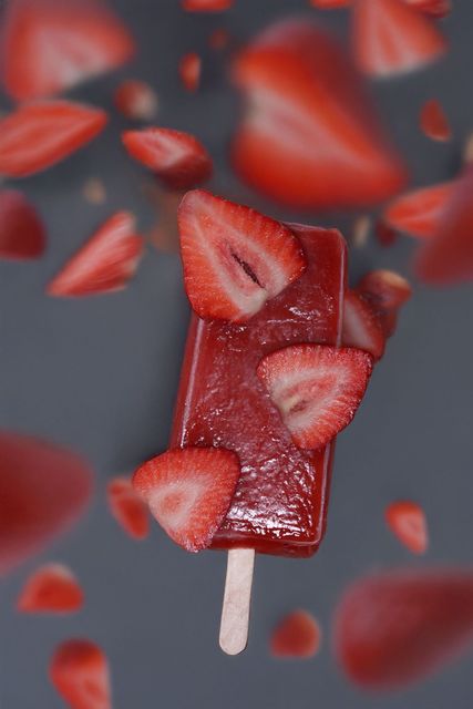Glace à la fraise avec des tranches de fraises sur une surface grise.