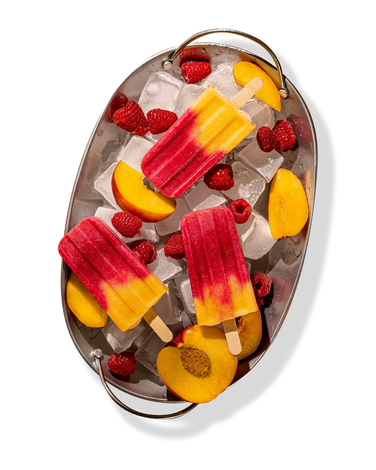 Plateau ovale avec glace, sucettes glacées à la pêche et à la framboise et fruits frais.