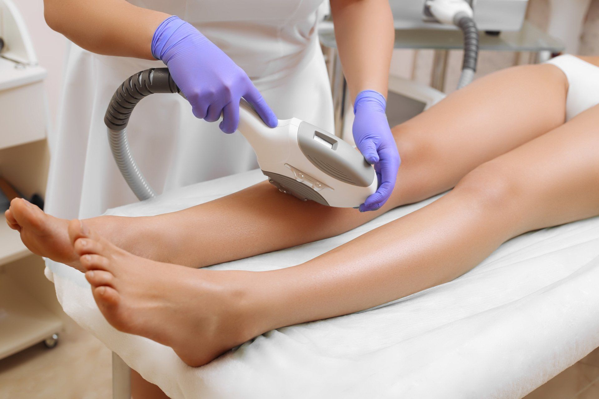professional administering laser hair removal on young womans legs