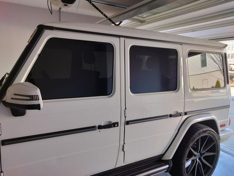 A white mercedes benz g class is parked in a garage.