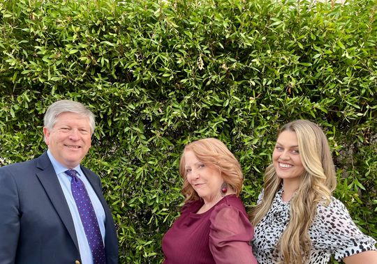 A photograph of the Pickering Law Corporation staff in front of a green bush backdrop in Redding, CA