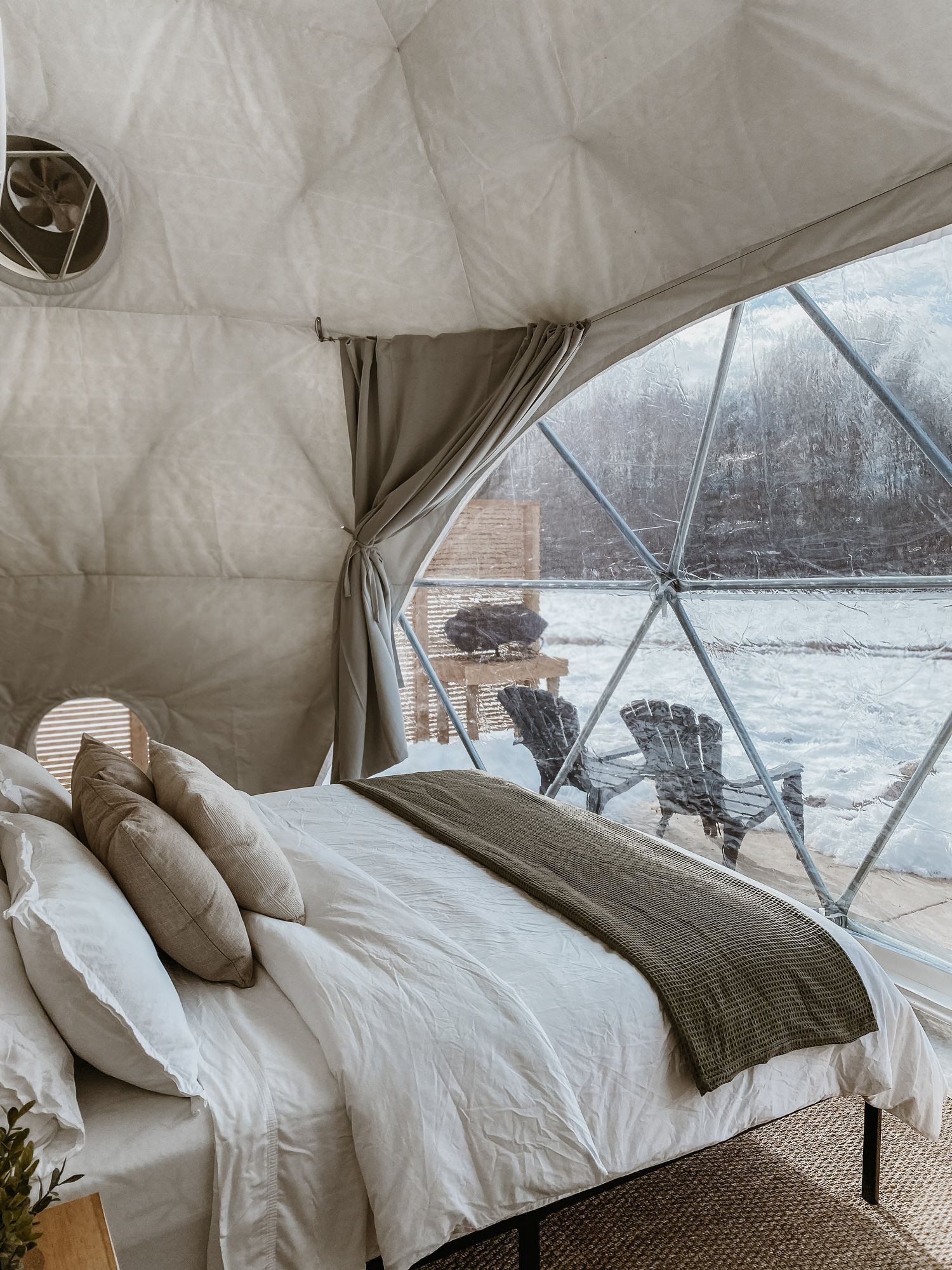 a bed in a dome with a view of a lake .