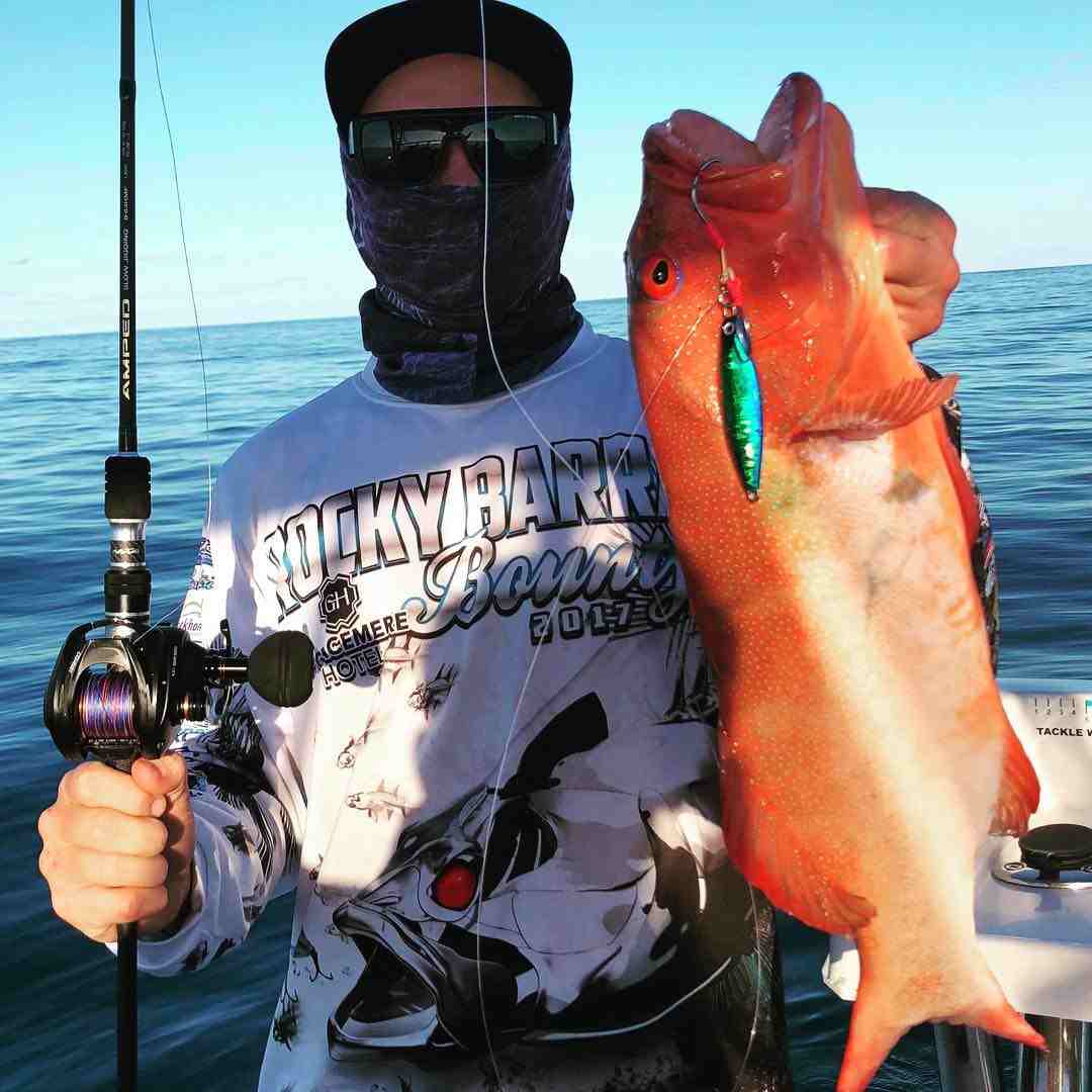 男子拿着鱼竿和一条橙色的鱼—开云体育app官网下载安装—钓鱼服装，在QLD的Yeppoon