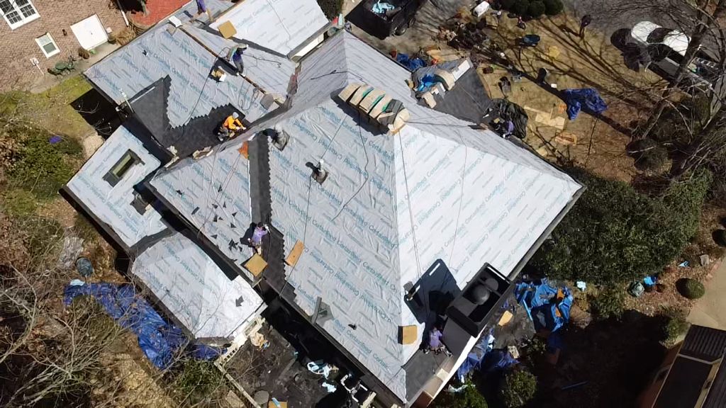 An aerial view of a house under construction with a roof being installed.