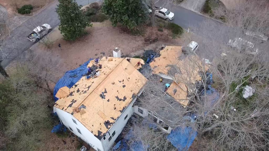 An aerial view of a house with a roof that is being repaired.