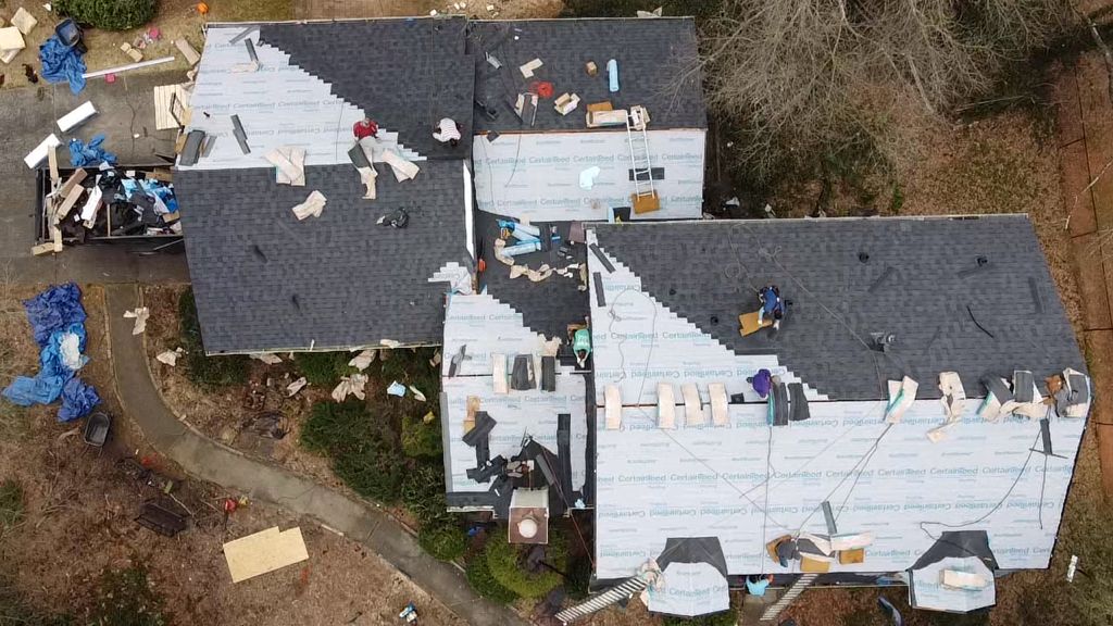An aerial view of a house under construction with a roof being installed.