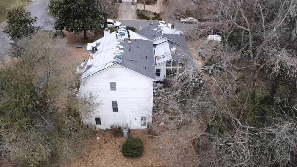 An aerial view of a white house surrounded by trees.