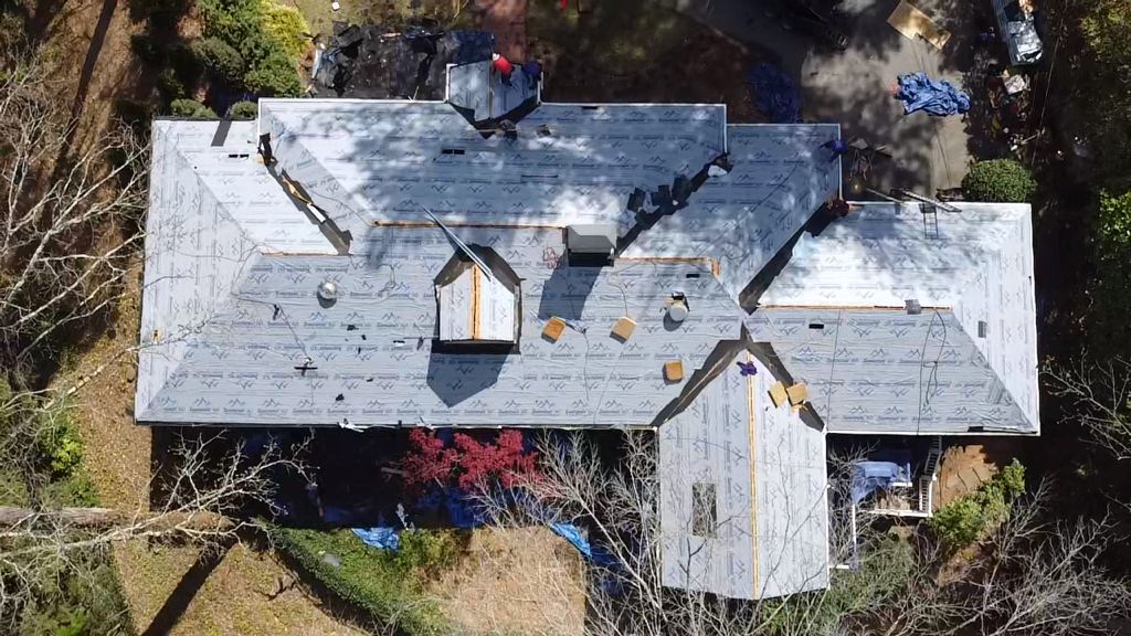 An aerial view of a house under construction with a roof being installed.