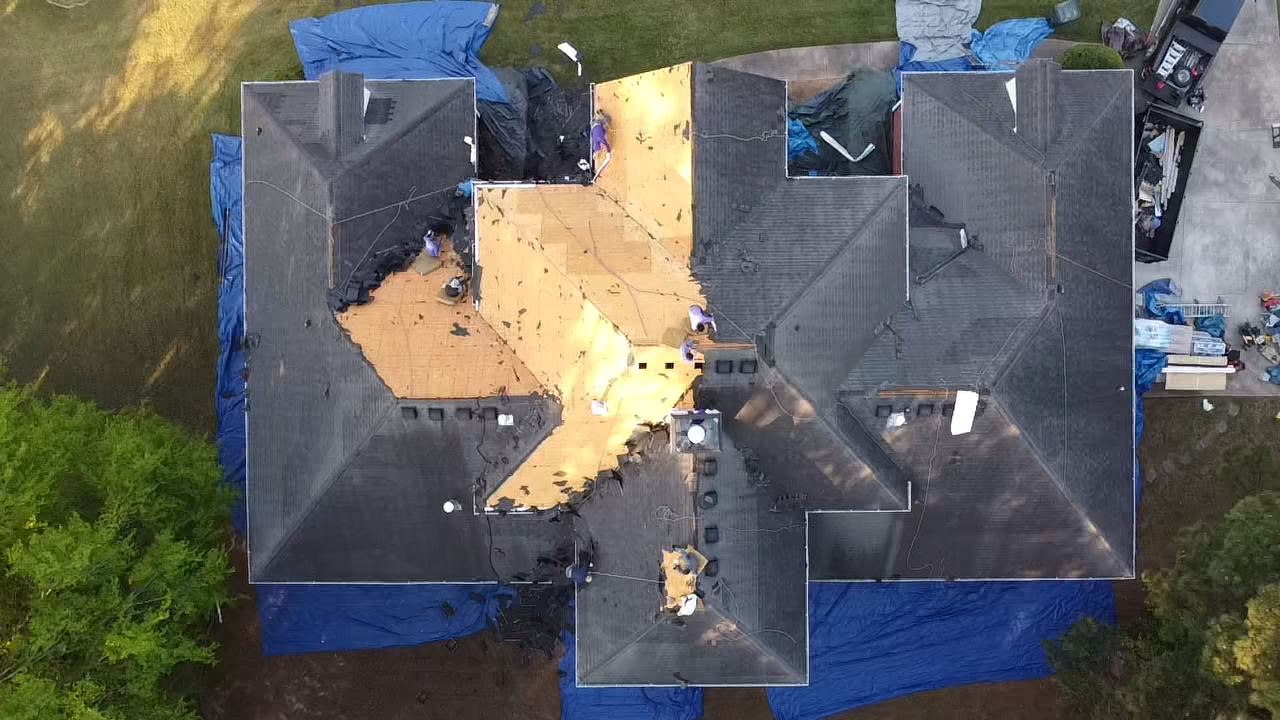 An aerial view of a house with a roof that is being repaired.