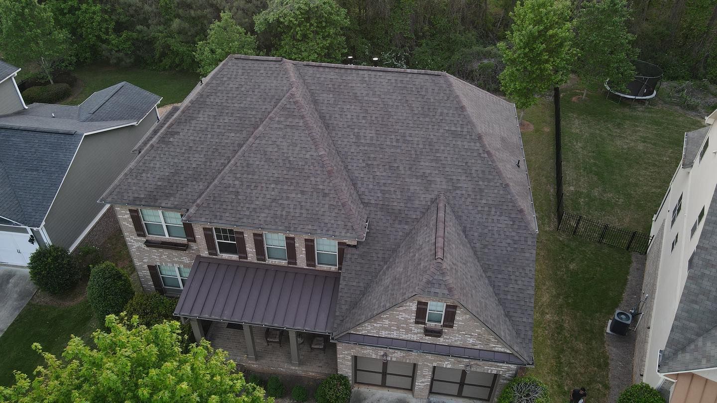 An aerial view of a large house with a gray roof in a residential area.