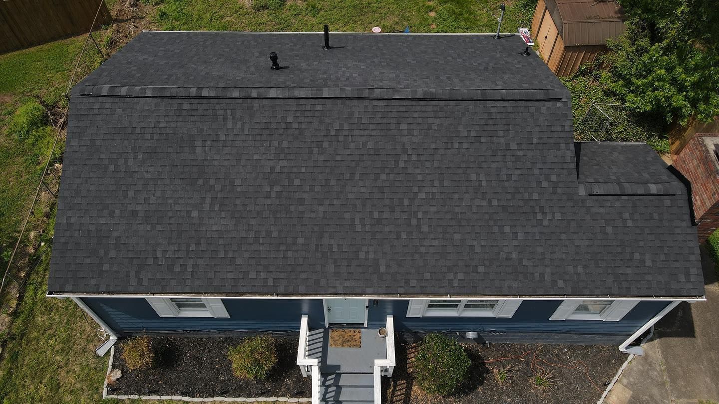 An aerial view of a blue house with a black roof.