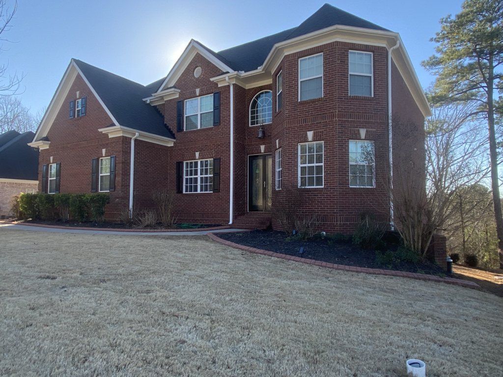 A large brick house with a black roof and a lot of windows.
