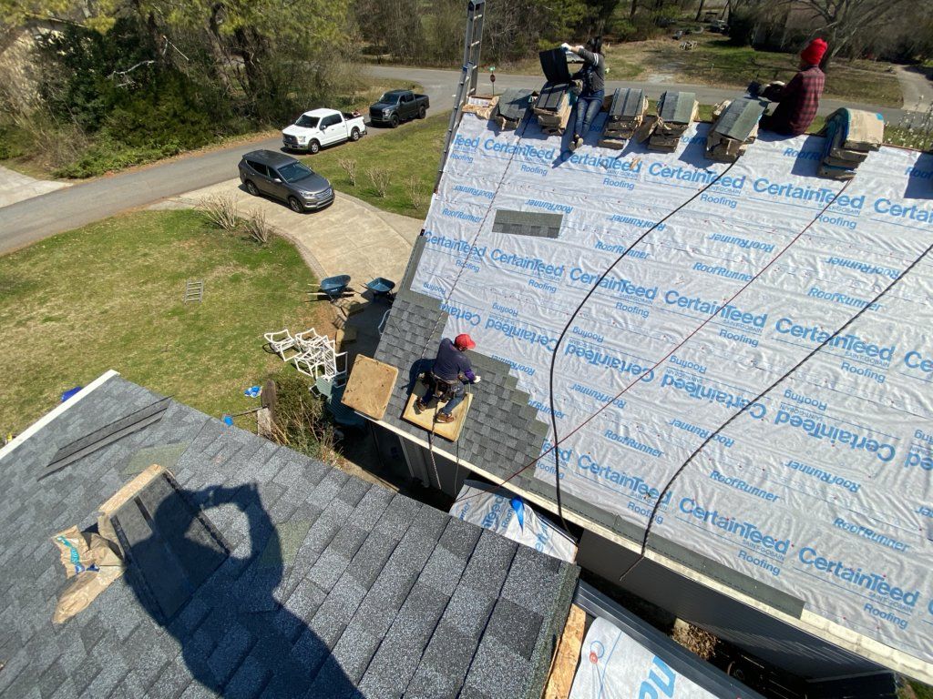 A group of people are working on the roof of a house.