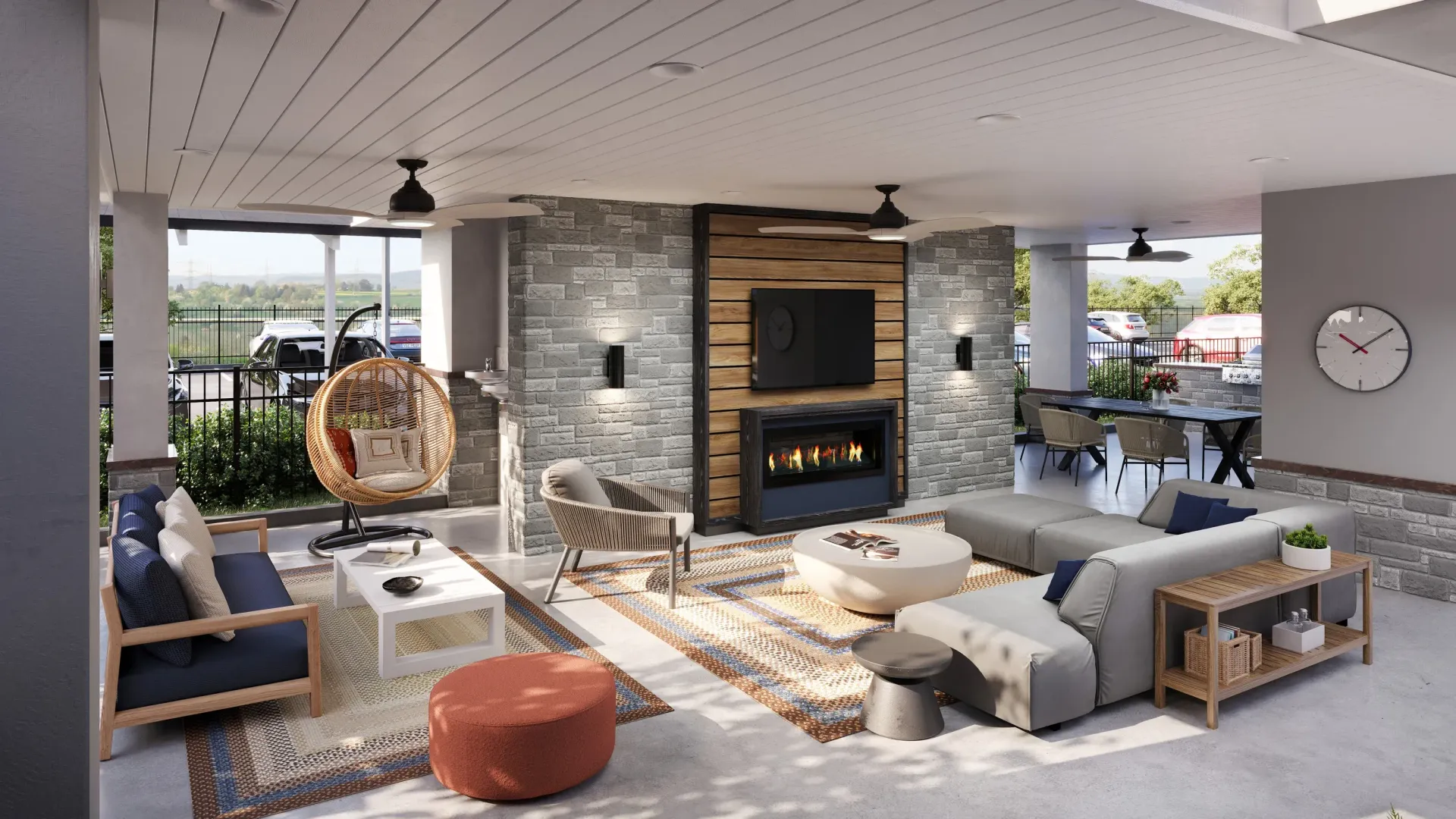 Covered outdoor community lounge with fireplace, wall TV, stone walls, and comfortable seating at The Astra Benders Landing, offers apartments for rent in Spring, TX, near I-45.