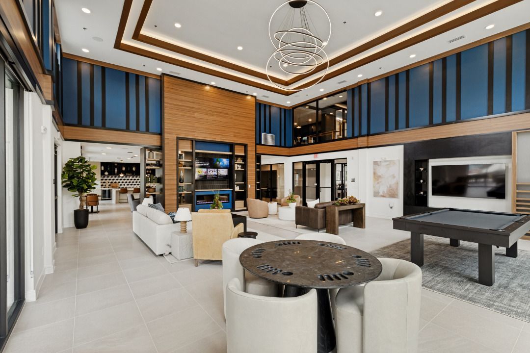 Modern luxury living room with white sofas, pool table, fireplace, and tall windows with blue curtains