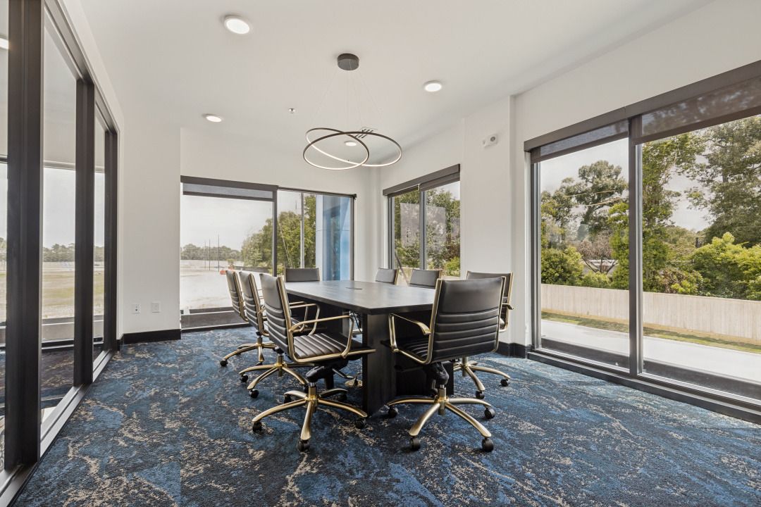 Modern conference room with glass walls, black chairs, and a long table on blue carpet