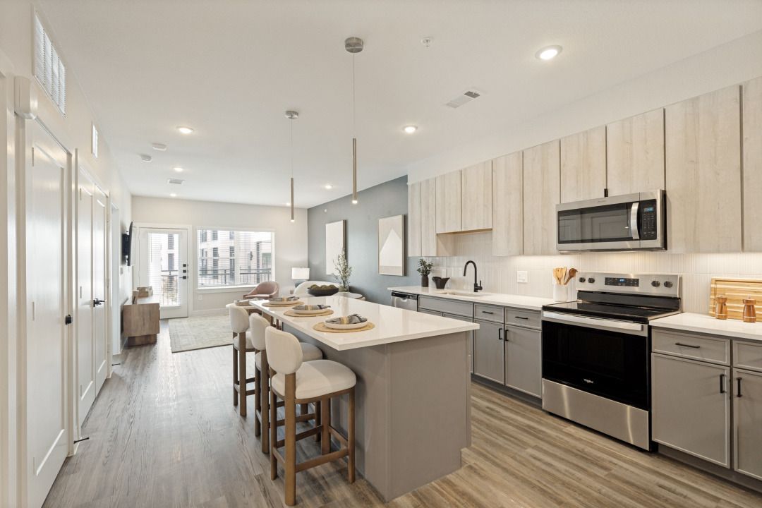 Bright modern kitchen with island, bar stools, stainless appliances, and light wood cabinets
