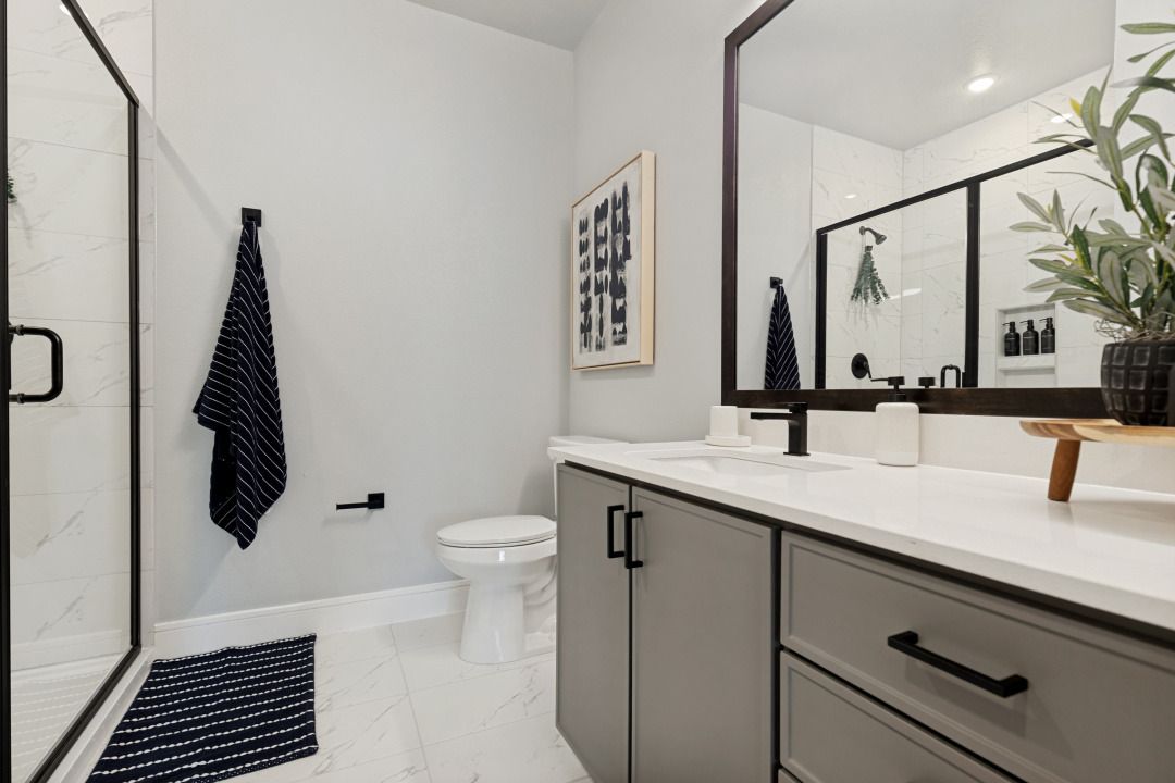 Modern bathroom with white tile, gray vanity, large mirror, and towel hanging on the wall