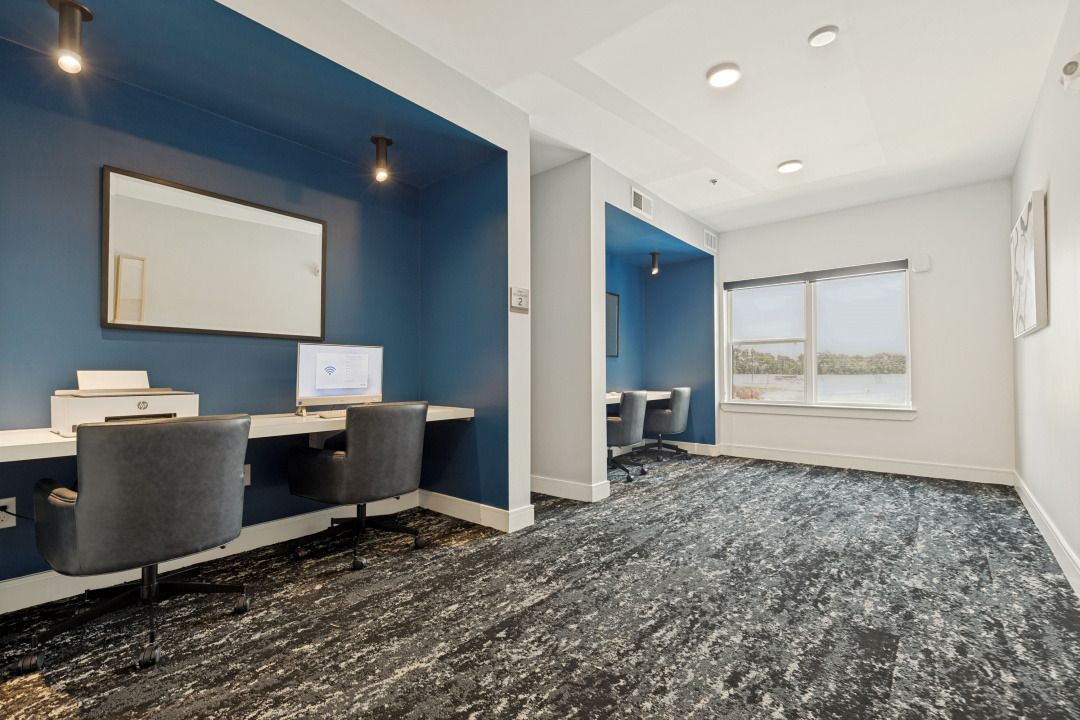 Modern office with blue accent wall, desks, chairs, and carpeted workspace.
