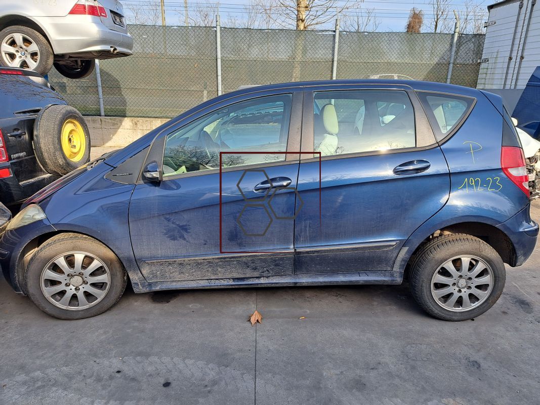 Un'auto blu è parcheggiata in un parcheggio vicino a una recinzione.