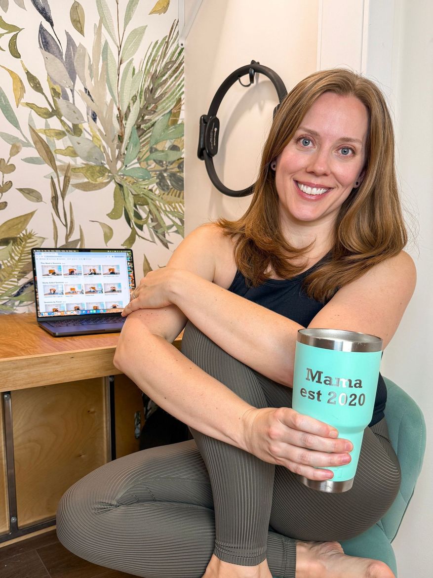 Pilates on demand, Pilates at home, Pilates for moms, Pilates, Postpartum Pilates. Amy sitting on green chair with laptop on desk.