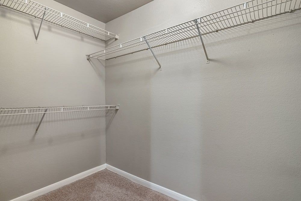 An empty walk-in closet with wire shelves and a carpeted floor at Marquis at Stonegate offers apartments for rent in Fort Worth, TX with WFH space.