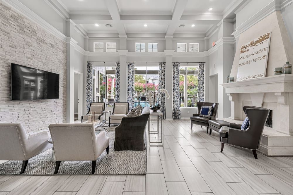 Spacious clubhouse is filled with furniture, a fireplace, and oversized windows at Marquis at Stonegate offers family-friendly apartments in Fort Worth, TX.