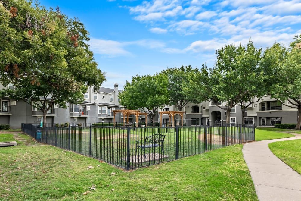 Apartment bark park with a fence and a bench at Marquis at Stonegate offers pet-friendly apartments in Fort Worth, TX.
