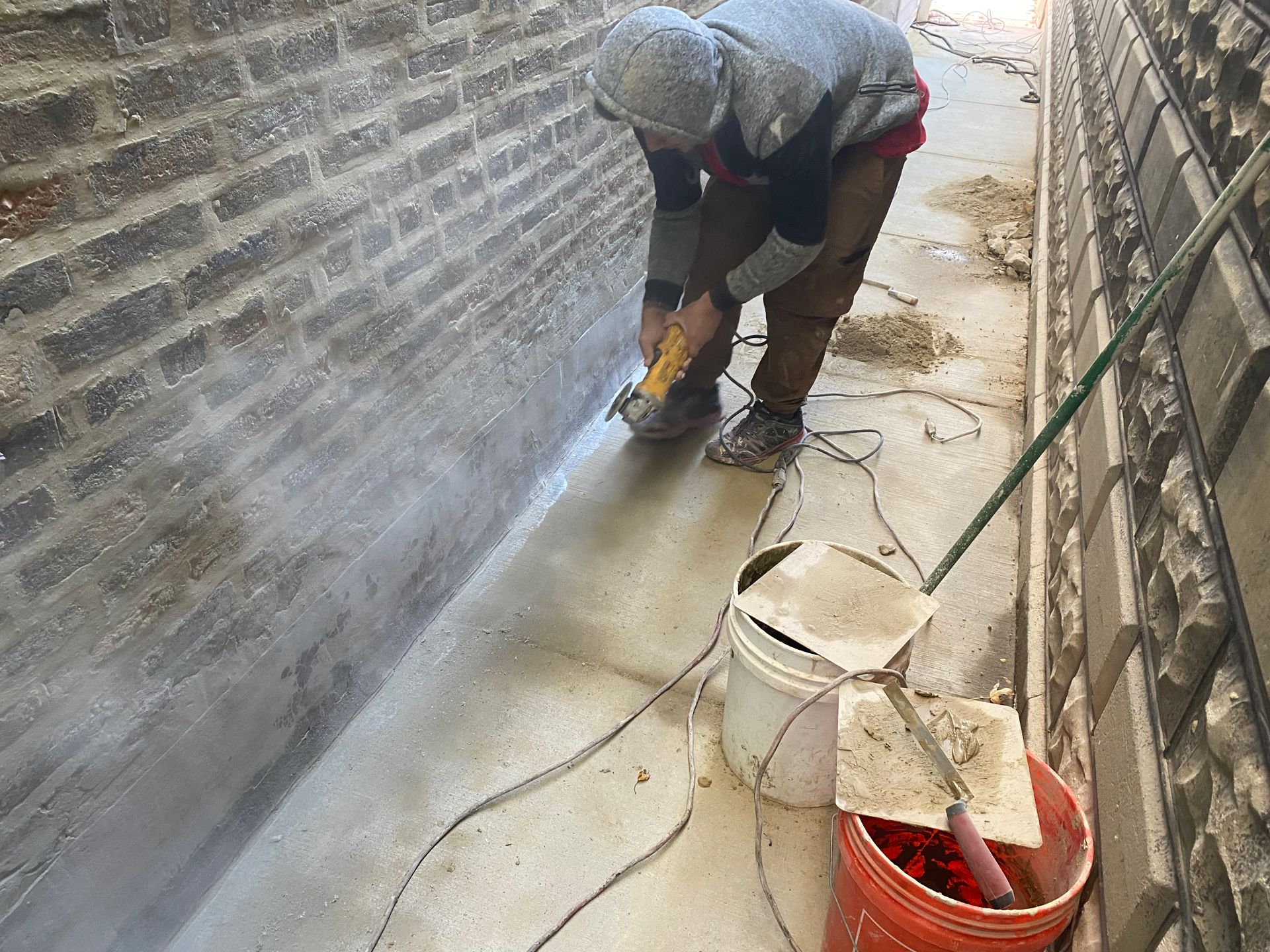 A man is using a grinder to cut a brick wall.