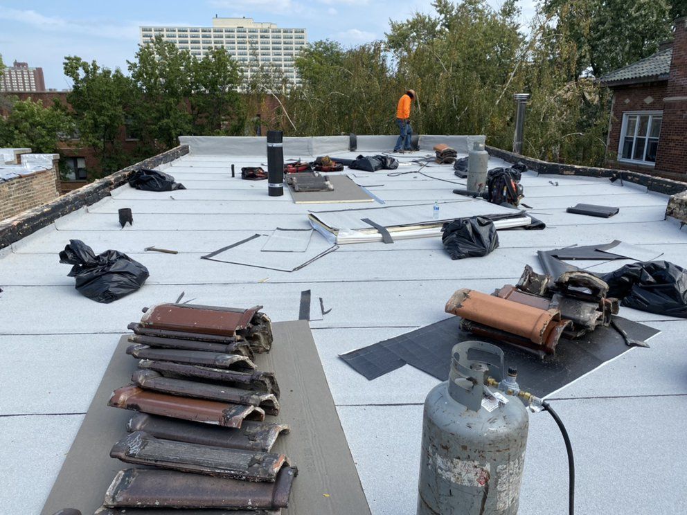 A man is working on a roof with a gas cylinder in the foreground