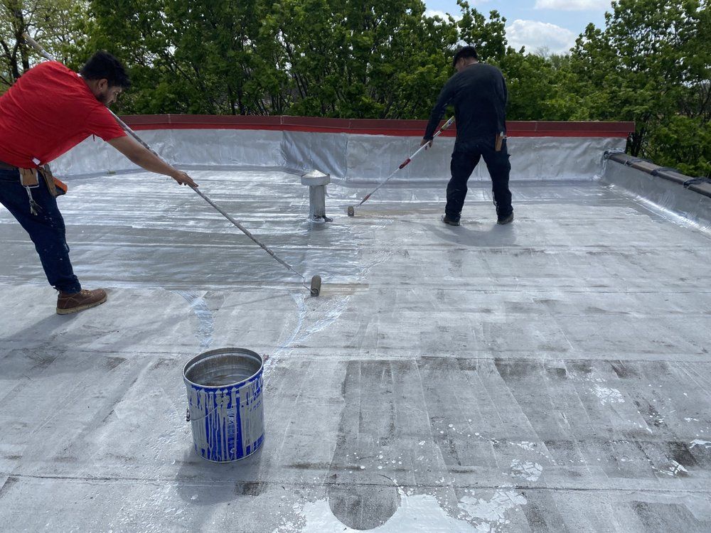 Two men are painting a roof with a roller.