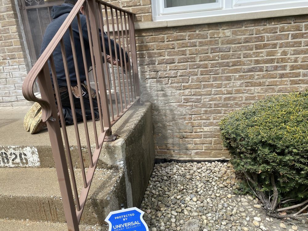 A man is cleaning the steps of a brick building.
