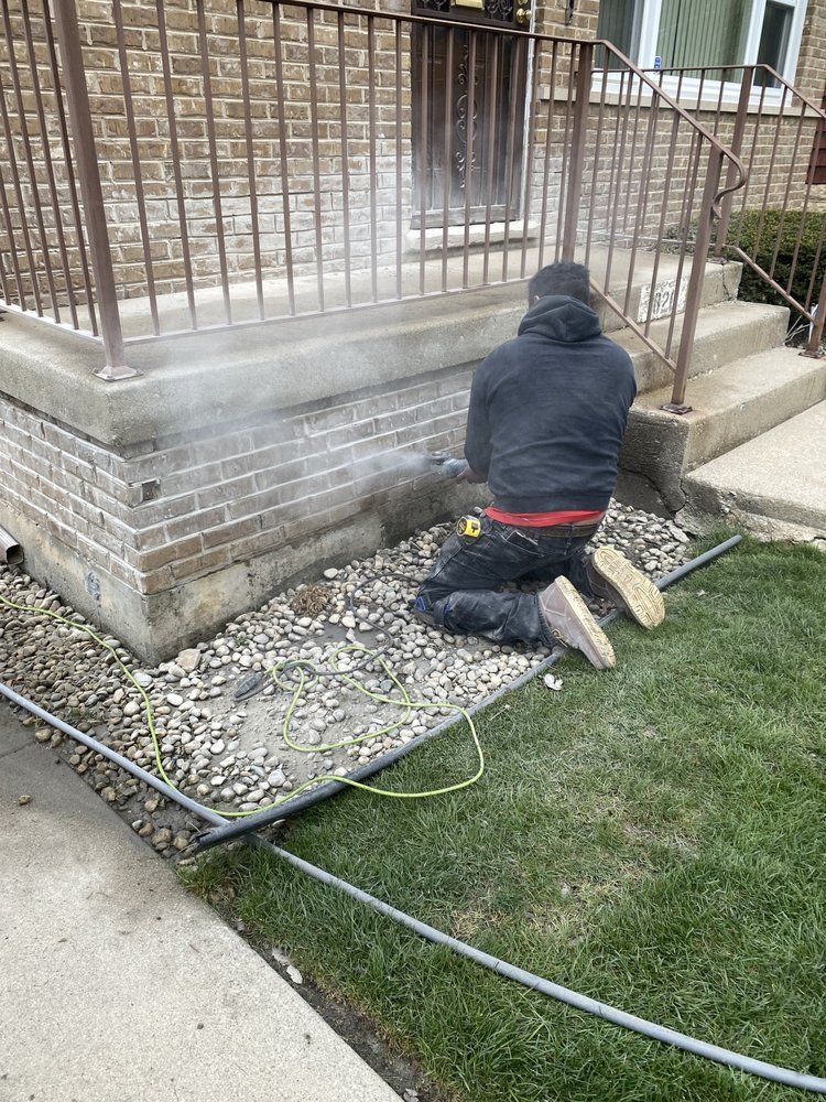 A man is kneeling down in front of a brick building.