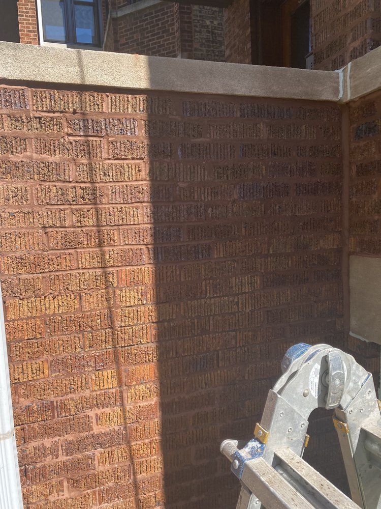 A man is standing on a ladder in front of a brick wall.