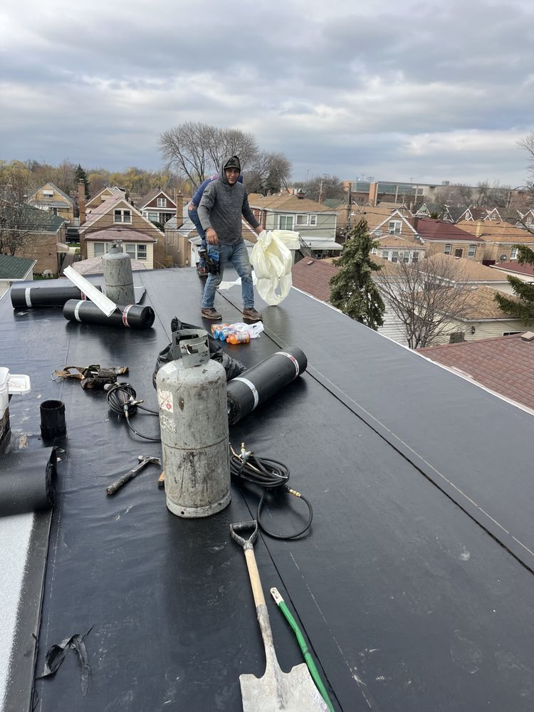 A man is standing on top of a black roof.