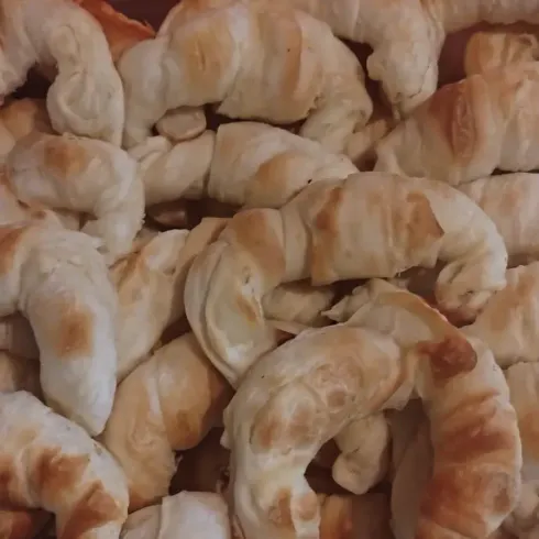 Primer plano de una pila de pasteles horneados de color marrón dorado con una forma hojaldrada y retorcida.
