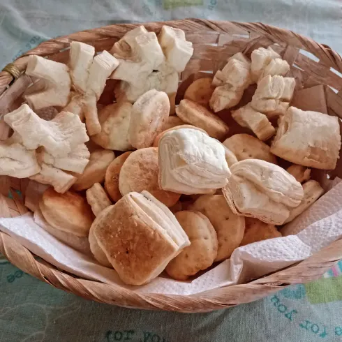 Cesta con trozos de pan variados sobre un paño blanco.