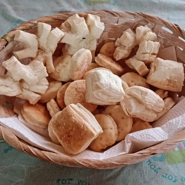 Cesta con trozos de pan variados sobre un paño blanco.