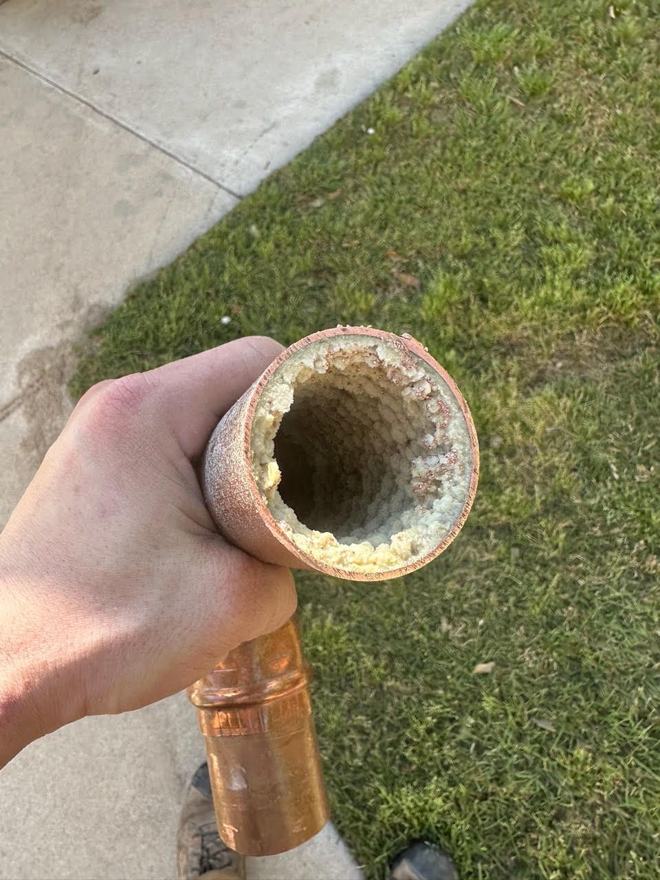 A person is holding a dirty copper pipe in their hand.