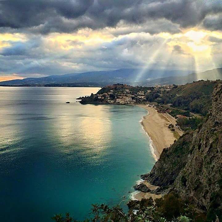 Il sole splende attraverso le nuvole sopra baia di Caminia