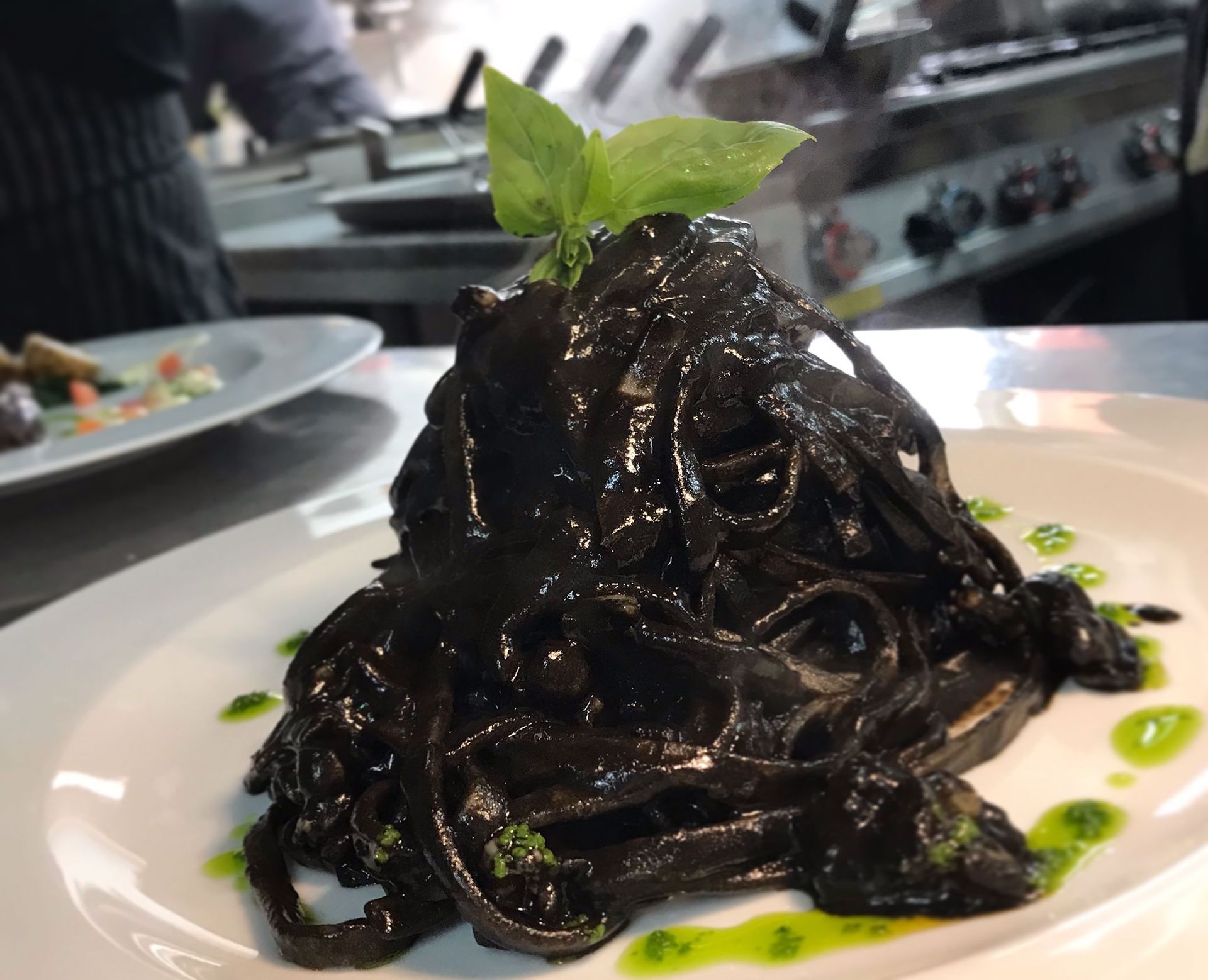 Un piatto bianco con sopra tagliatelle nere e salsa verde