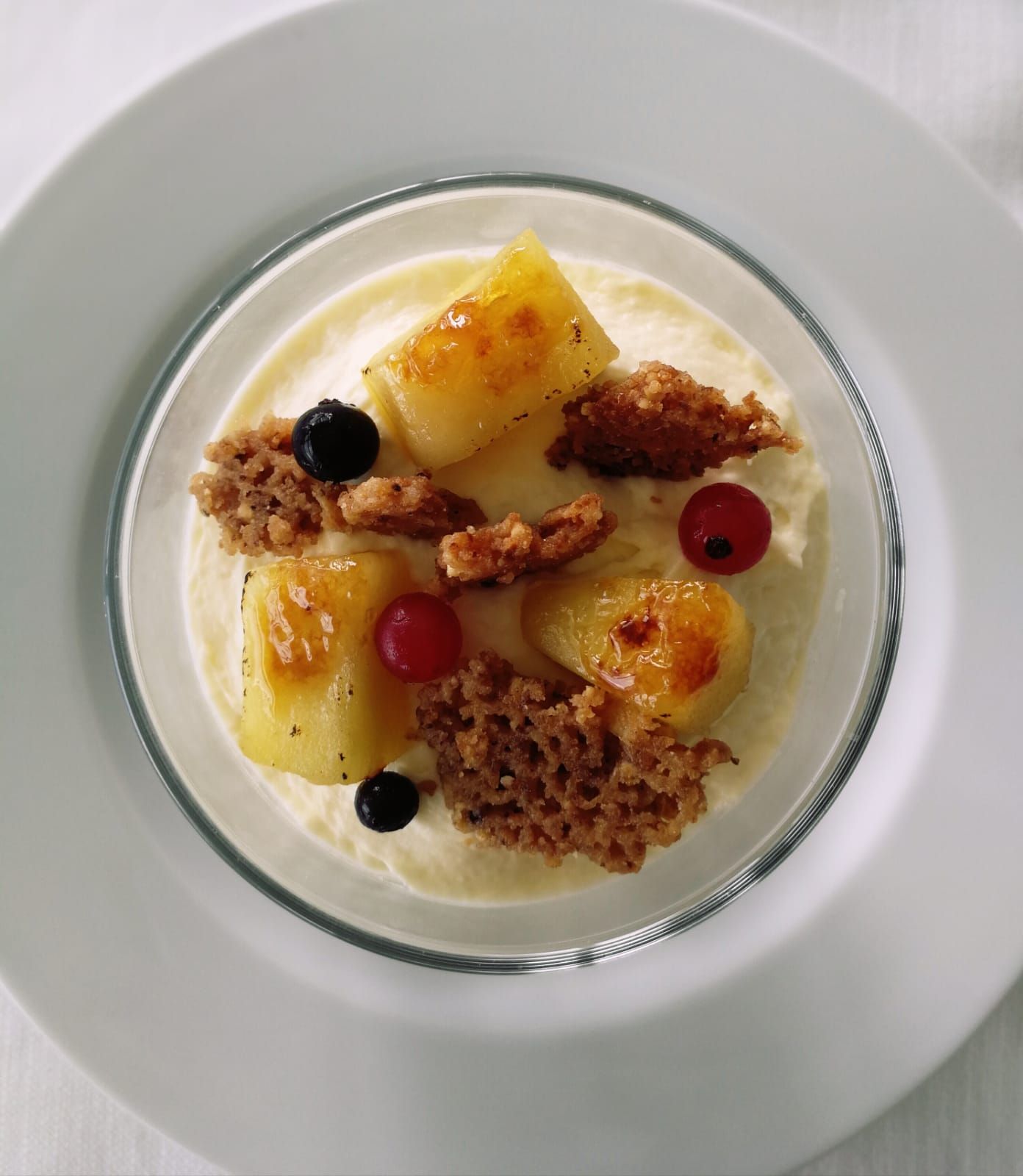 Un piatto bianco sormontato da un dessert con ananas e frutti di bosco