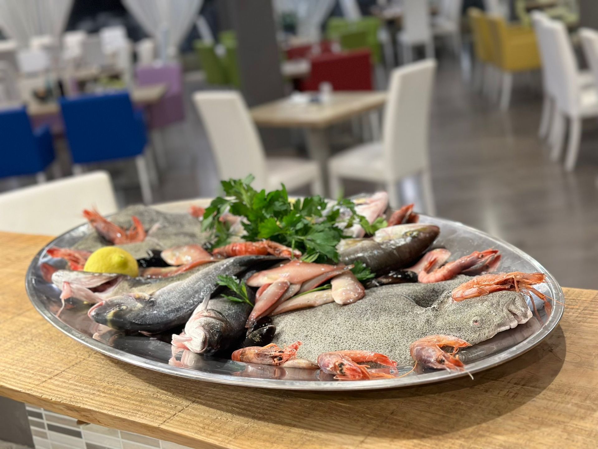 Un piatto di pesce e gamberi su un tavolo di legno alla Tavernetta, ristorante con menù di pesce in provincia di Catanzaro