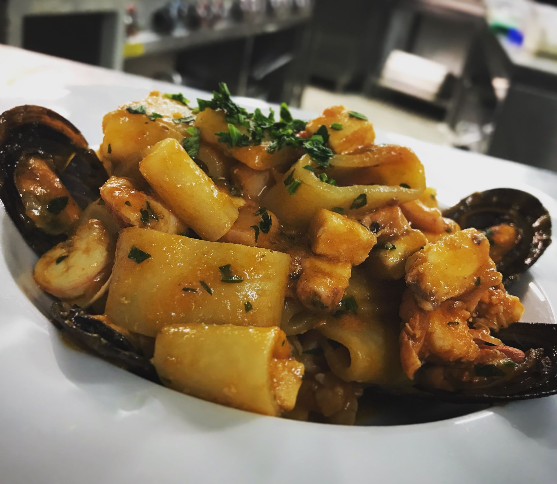 Un primo piano di un piatto di pasta con frutti di mare su un piatto bianco