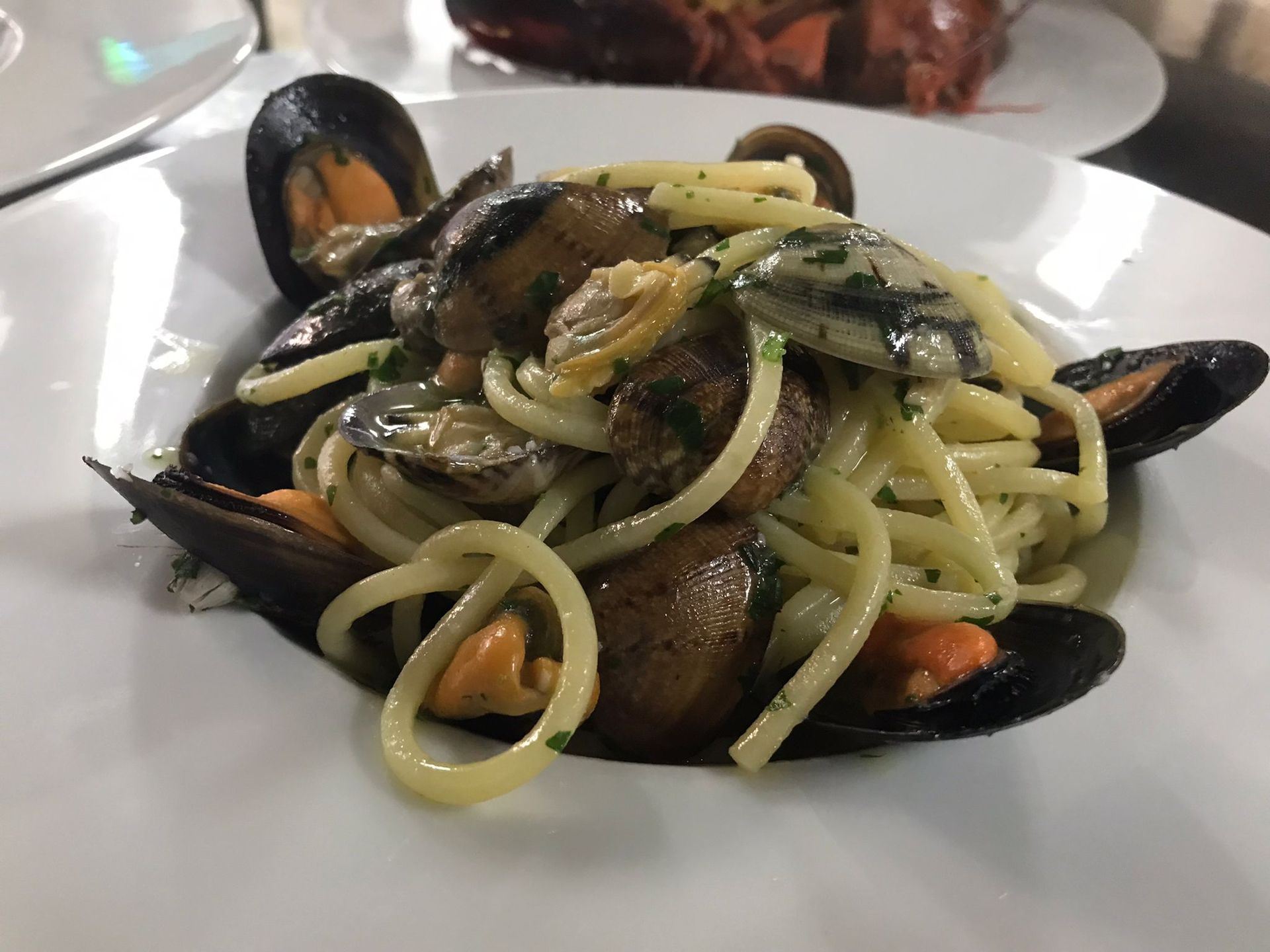Un piatto di spaghetti con cozze e funghi su un tavolo.