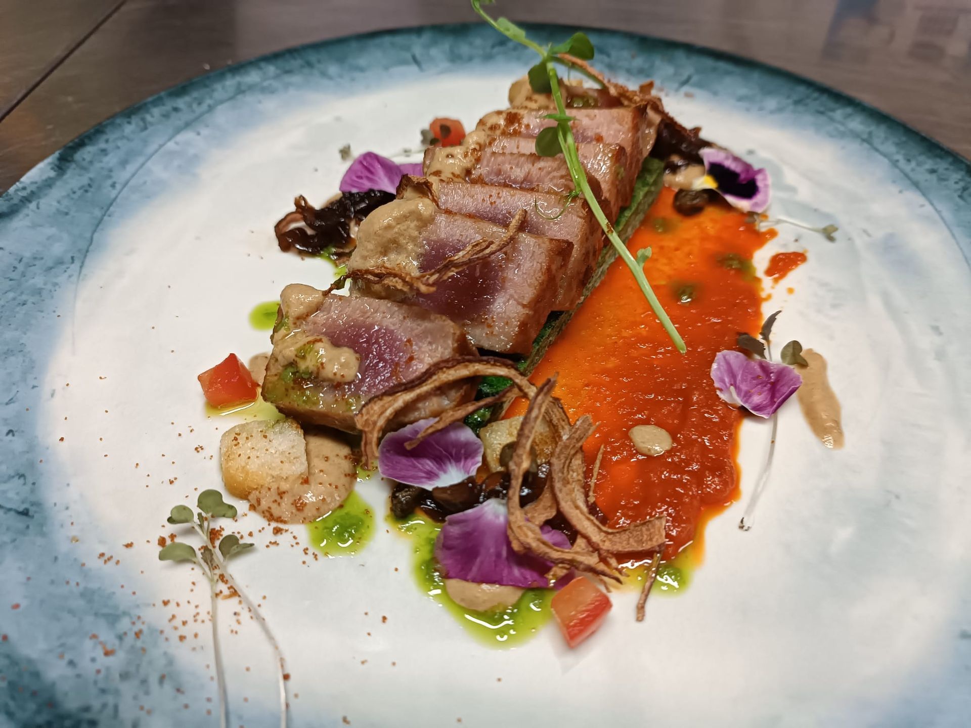 Un piatto bianco con sopra tonno e verdure su un tavolo.