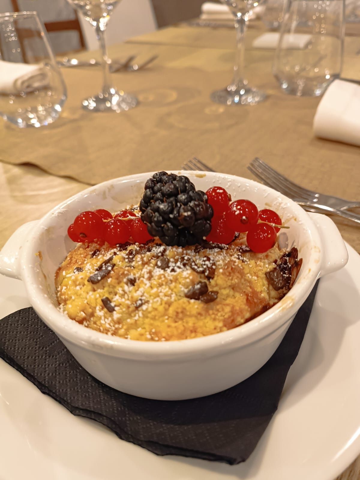 Una ciotola di cibo con delle bacche sopra è su un piatto su un tavolo.