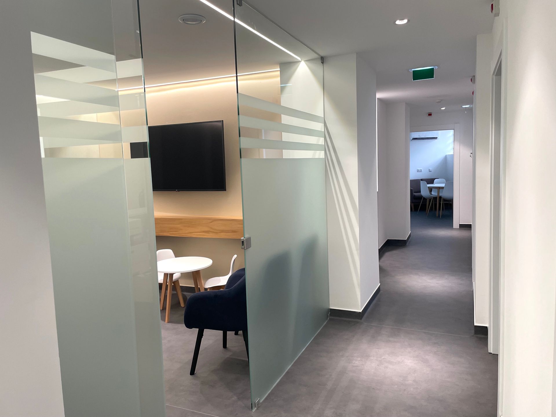 Corredor iluminado com portas de vidro na clínica Greenmed.
