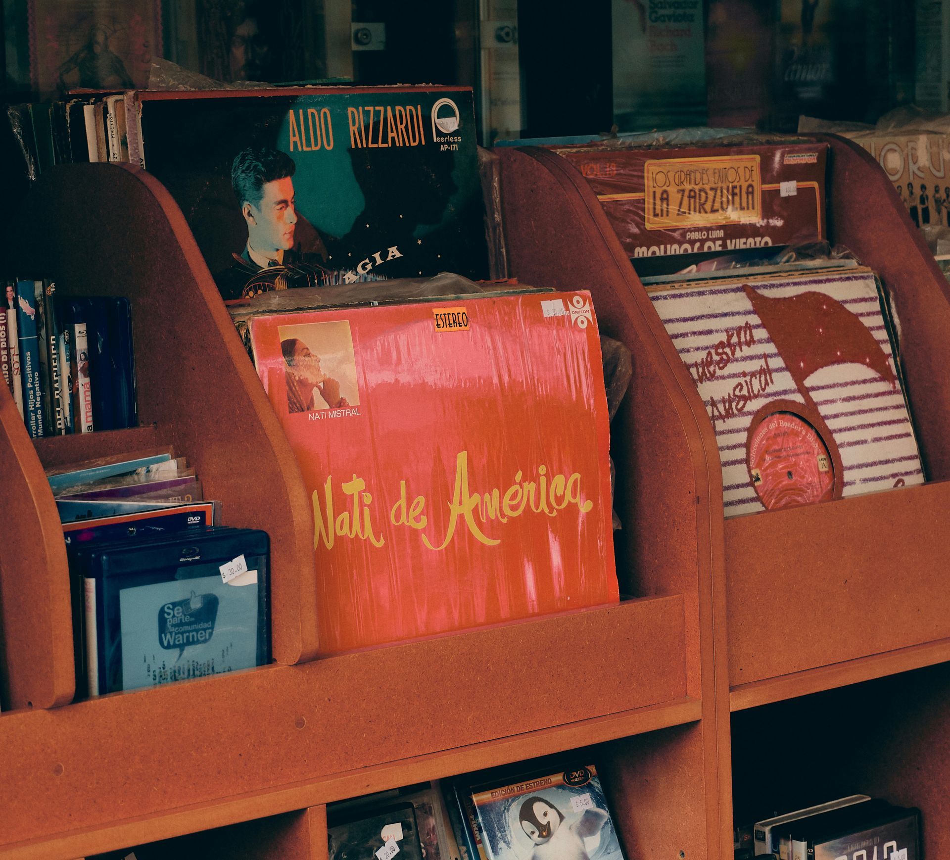 Wooden shelves filled with vintage vinyl records, including a prominent orange cover titled 