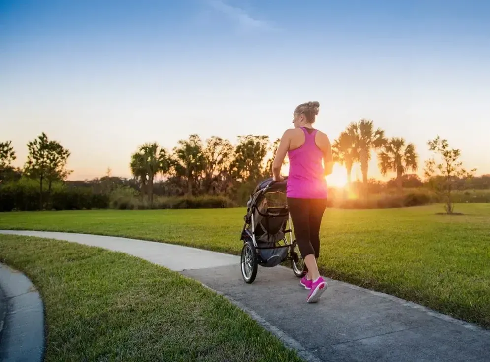 A Woman is Pushing a Stroller Down a Path in a Park — Hire All in Tugun, QLD